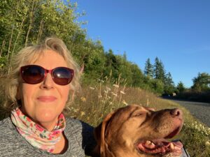 A woman and her dog are standing in the grass.